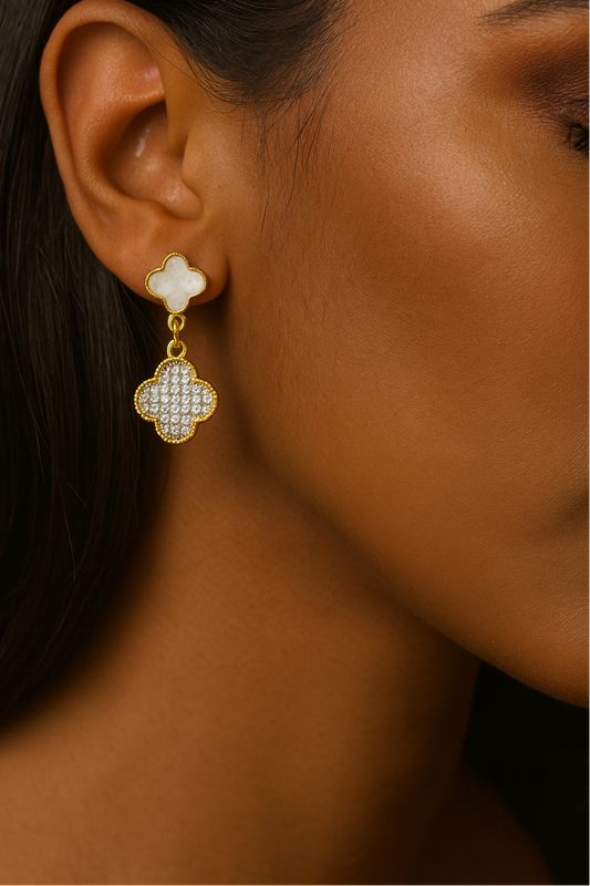 Close-up of a person wearing a gold and white clover-shaped earring.