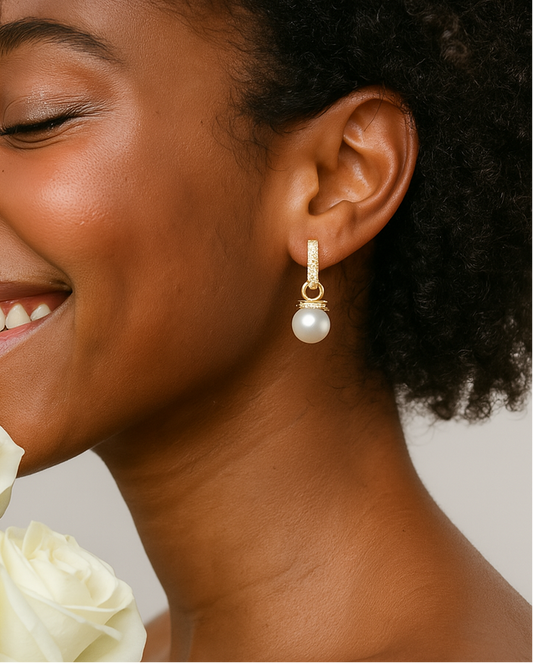 Close-up of a woman wearing a pearl earring with a neutral background