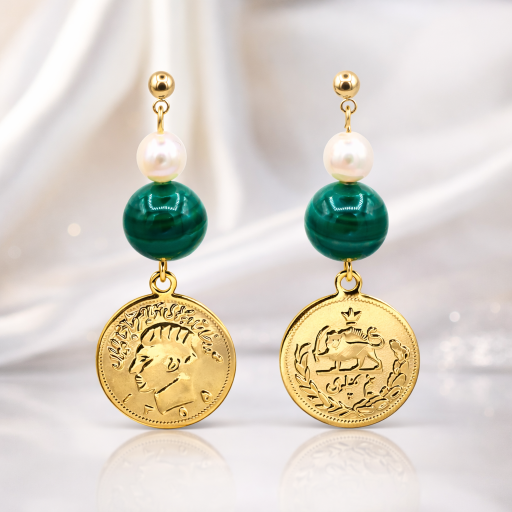 Pair of earrings with gold coins, green beads, and pearls on a reflective surface.