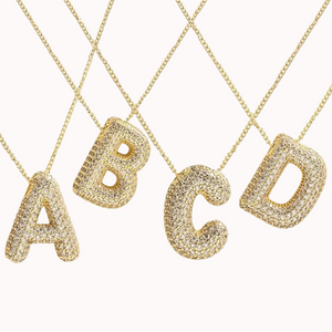 A set of four gold-plated initial necklaces with the letters 'ABCD', each encrusted with sparkling zirconia stones.