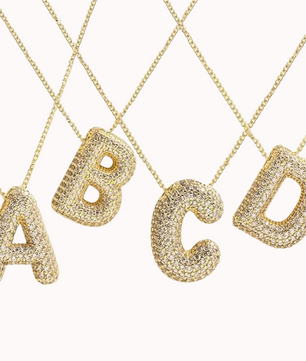 A set of four gold-plated initial necklaces with the letters 'ABCD', each encrusted with sparkling zirconia stones.