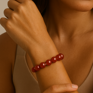 Woman wearing a red beaded bracelet on her wrist against a neutral background