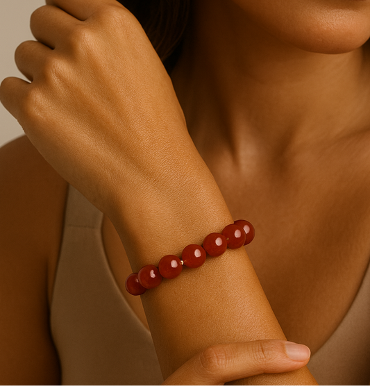 Woman wearing a red beaded bracelet on her wrist against a neutral background
