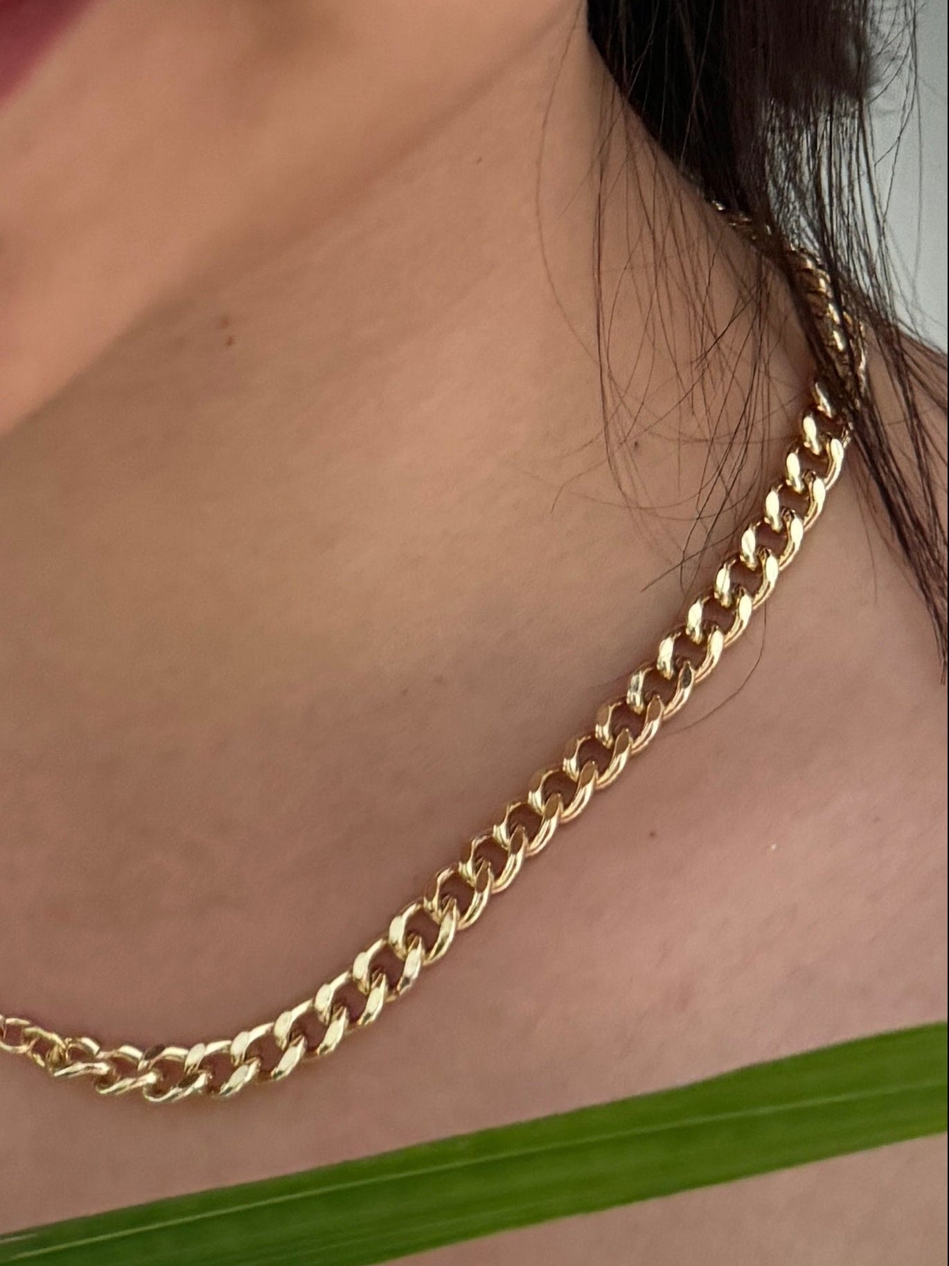 Gold chain necklace worn by a person with a blurred background
