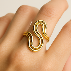 Gold ring with a wavy design on a finger against a neutral background
