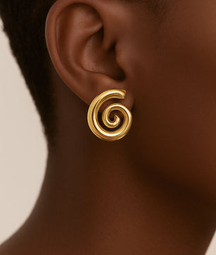 Gold spiral earring on a person's ear with a neutral background