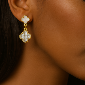 Close-up of a person wearing a gold and white clover-shaped earring.