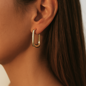 Gold hoop earring worn by a person with a neutral background