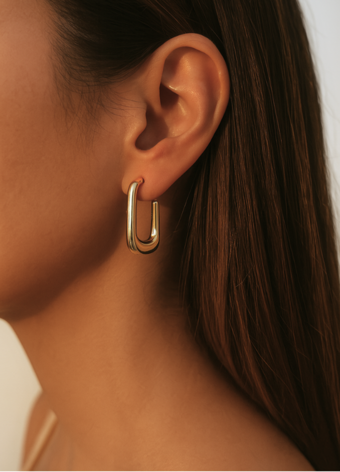 Gold hoop earring worn by a person with a neutral background