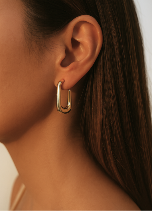 Gold hoop earring worn by a person with a neutral background