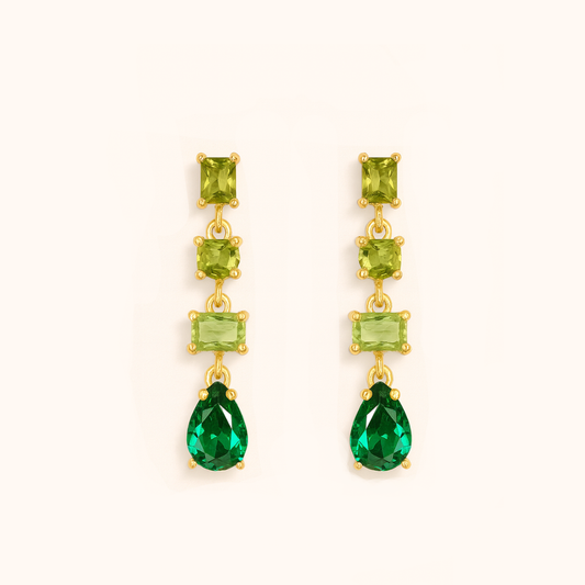Pair of gold earrings with green gemstones on a white background