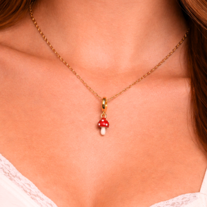 Necklace with a red mushroom pendant on a person wearing a white lace top.