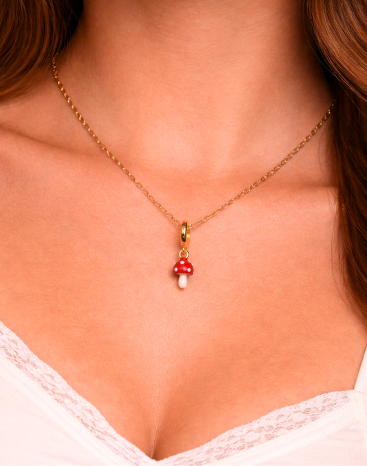 Necklace with a red mushroom pendant on a person wearing a white lace top.
