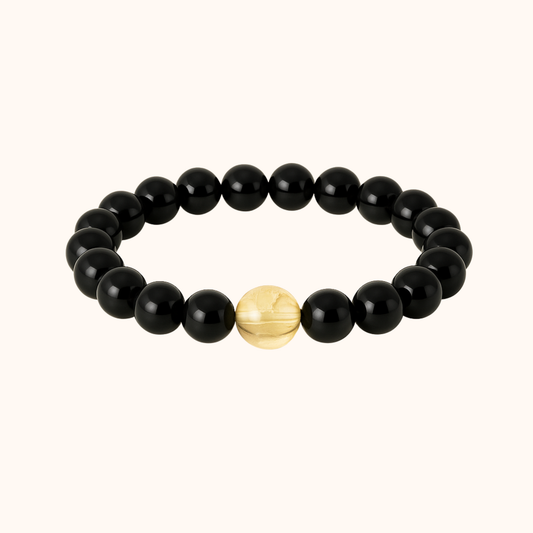 Black beaded bracelet with a gold accent bead on a white background