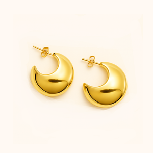 Gold hoop earrings on a light beige background