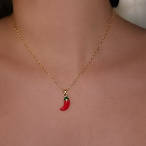 Gold necklace with a red chili pepper pendant on a person's neck