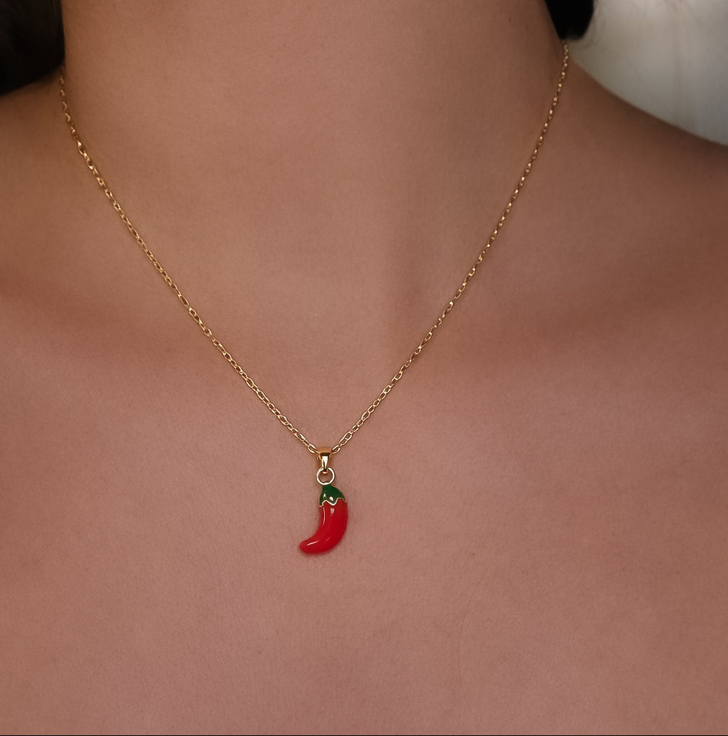 Gold necklace with a red chili pepper pendant on a person's neck