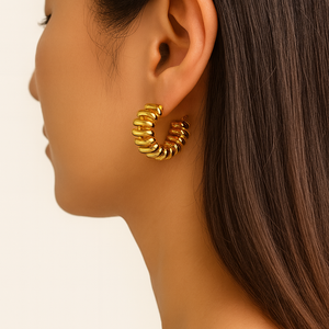 Gold hoop earring worn by a model on a plain background