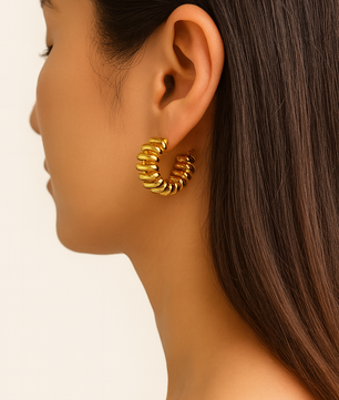 Gold hoop earring worn by a model on a plain background