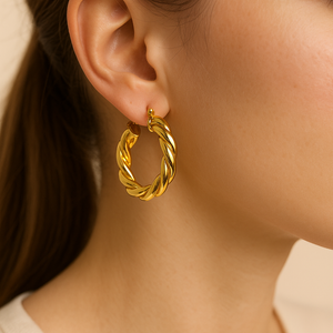 Close-up of a person wearing a gold hoop earring with a neutral background