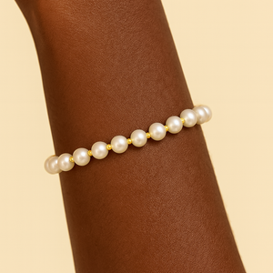 Pearl bracelet on a wrist against a beige background