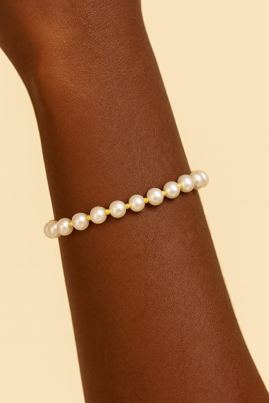 Pearl bracelet on a wrist against a beige background