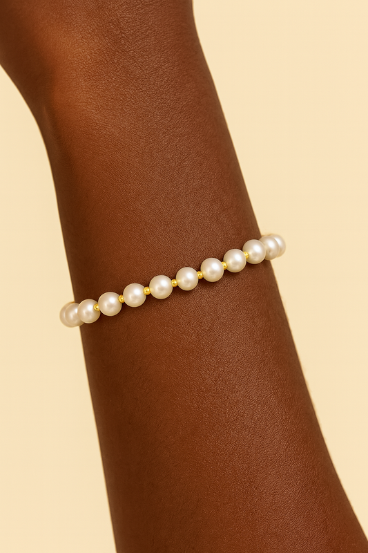 Pearl bracelet on a wrist against a beige background