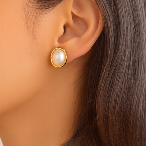 Close-up of an ear wearing a gold earring with a pearl center.