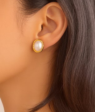 Close-up of an ear wearing a gold earring with a pearl center.