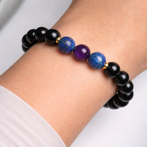 Bracelet with black, blue, and purple beads on a wrist against a white background
