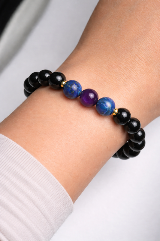 Bracelet with black, blue, and purple beads on a wrist against a white background